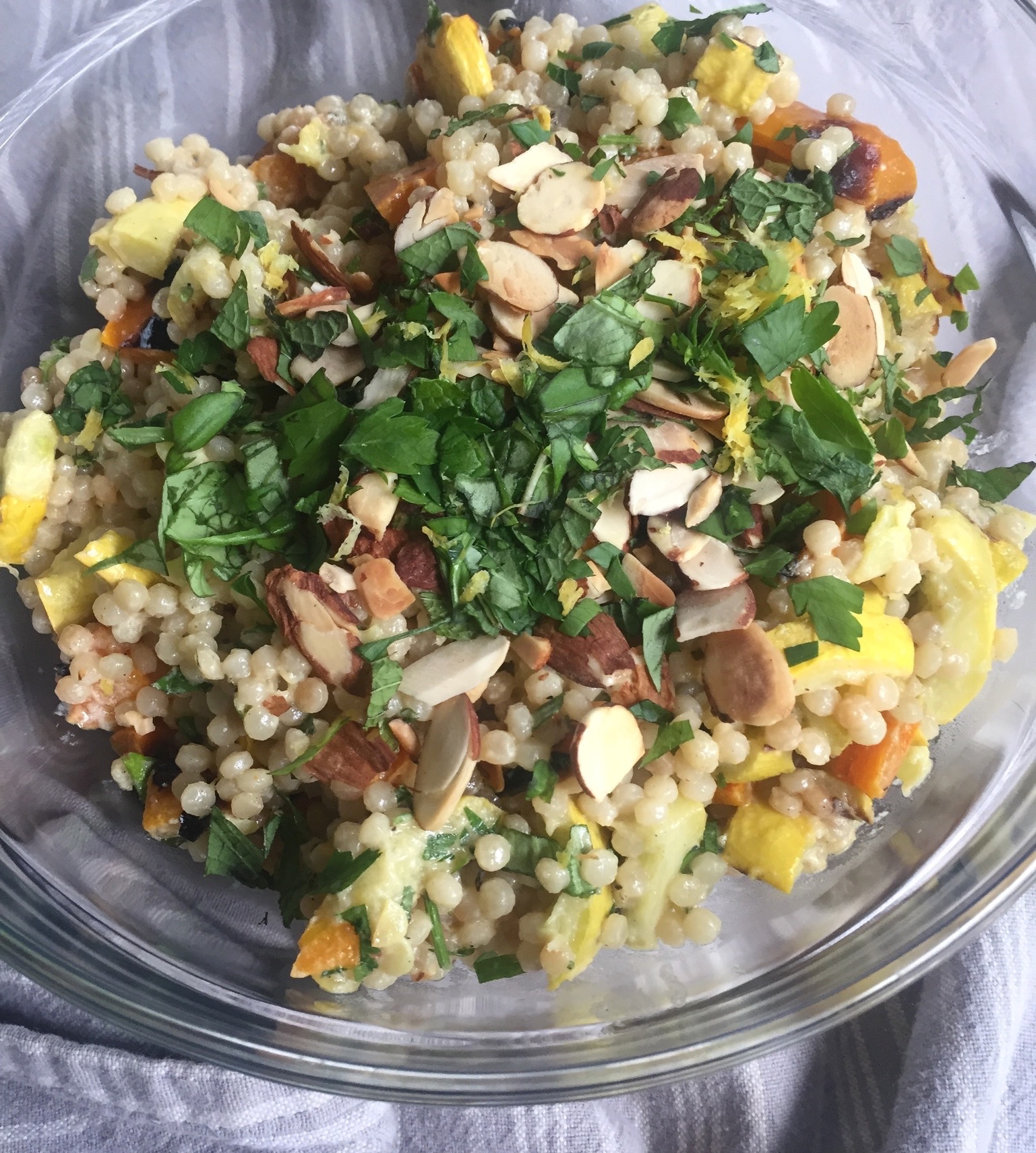 Overhead bowl of Israeli couscous with grilled vegetables and tahini